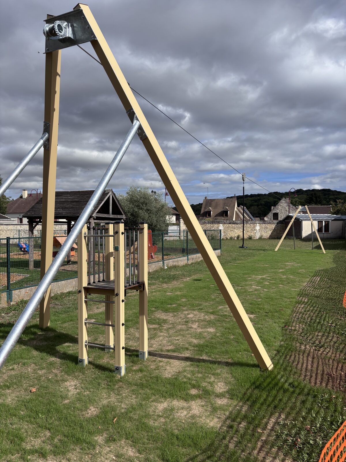 Tyrolienne avec portique et plateforme de départ dans un parc à Breuil-le-Sec (Oise), aire de jeux clôturée en arrière-plan — référence Arena Jeux